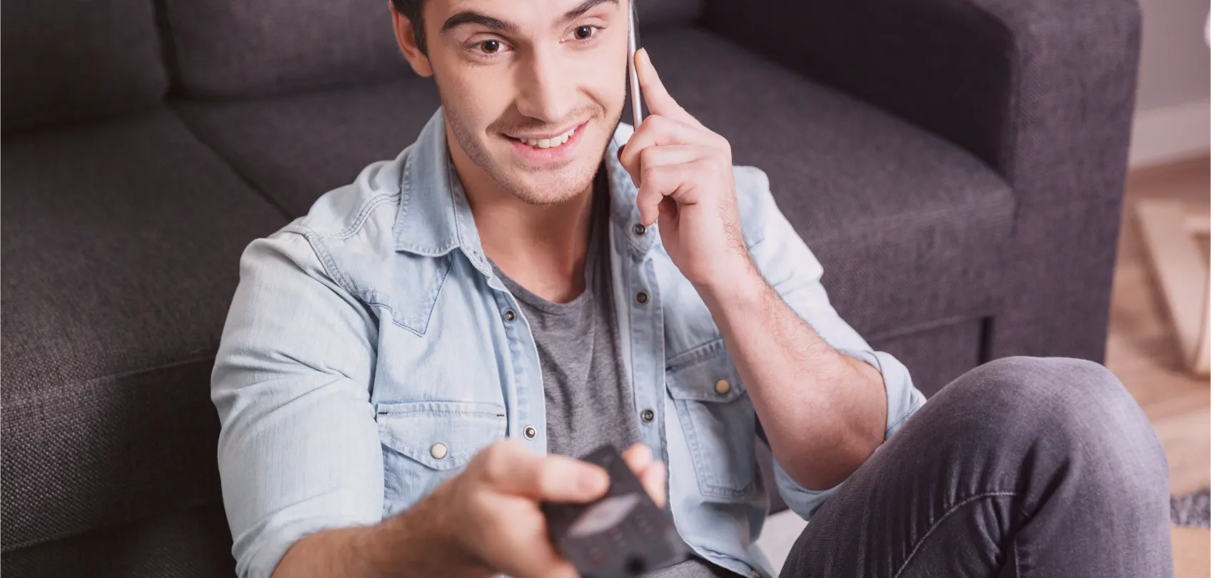 Young woman smiling while talking on the phone and holding a remote control, representing multiple communication channels in an omnichannel experience.